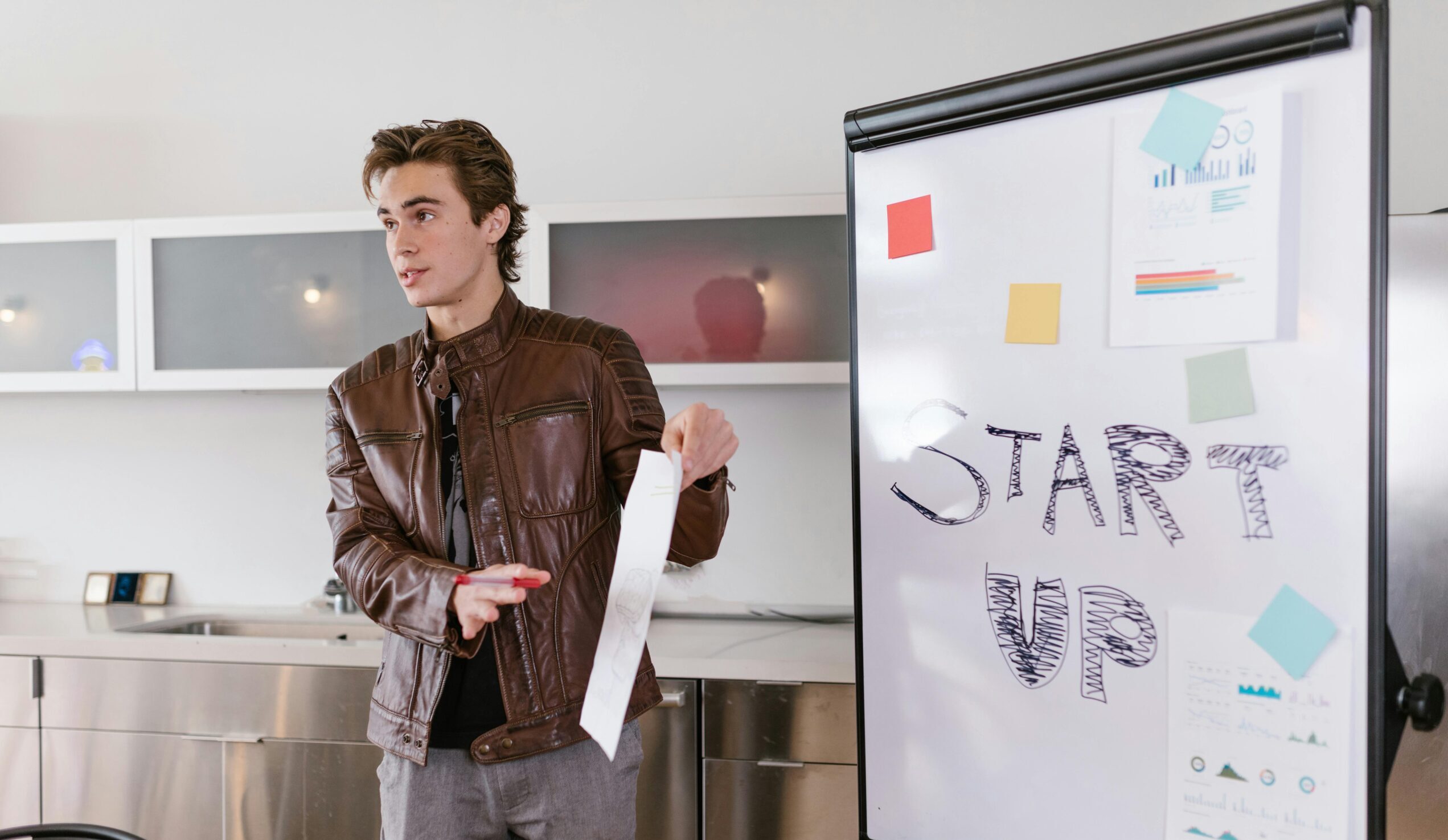 A young entrepreneur gives a presentation on startup strategies indoors with a flip chart.