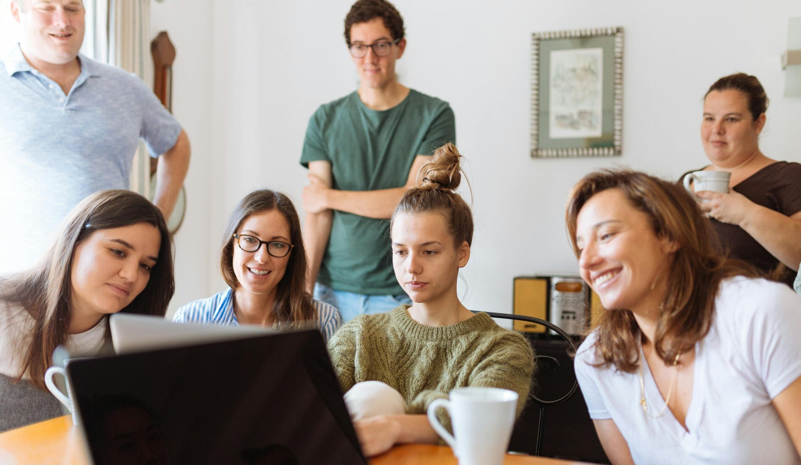 A diverse group of adults at work, enjoying a casual meeting indoors with focus and smiles.