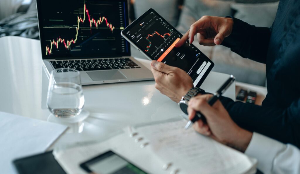 Business professionals reviewing financial charts on digital devices in a modern office setting.